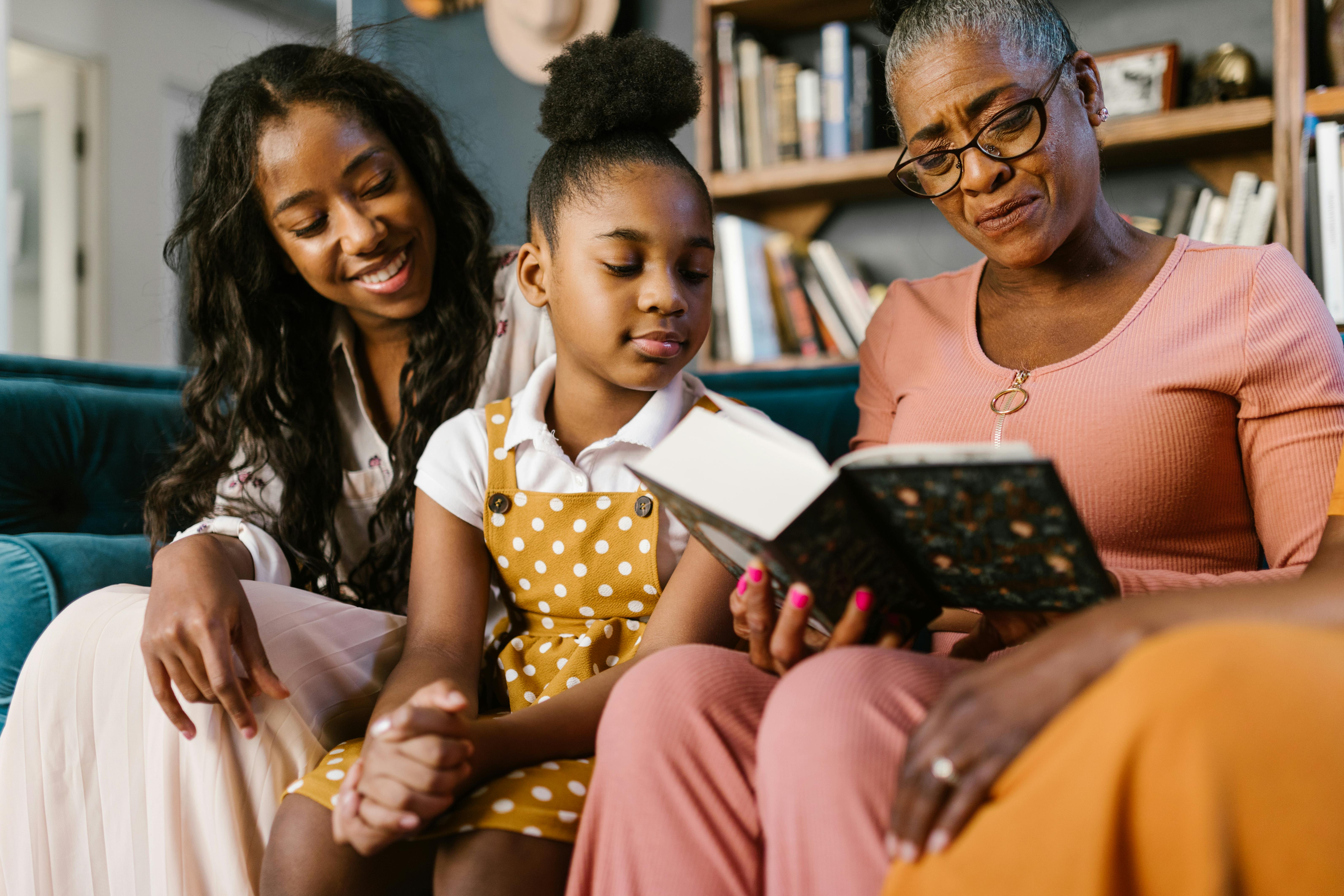 A joyful family gathering with three generations reading a book together indoors.