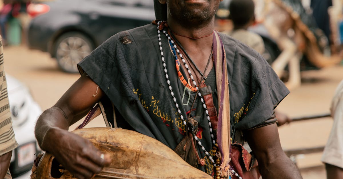 An African griot in traditional performance on a lively street.